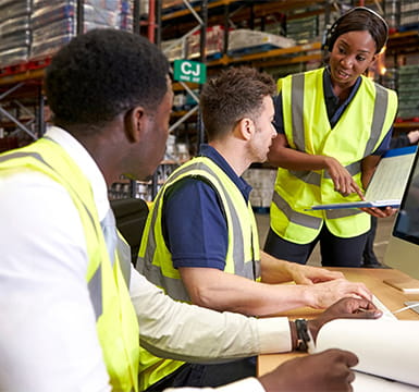 warehouse workers reviewing documents on screen