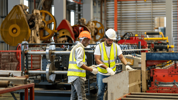 Workers on an assembly line in a factory, focusing on their tasks with machinery and equipment around them.