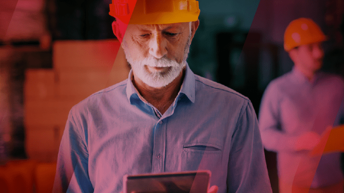 Mature worker wearing a hard hat looking at a tablet
