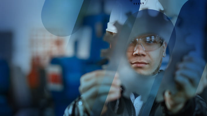 engineer in hard hat peering through a gear
