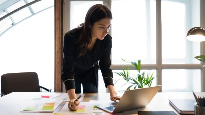A confident young business person studying a report on their laptop.
